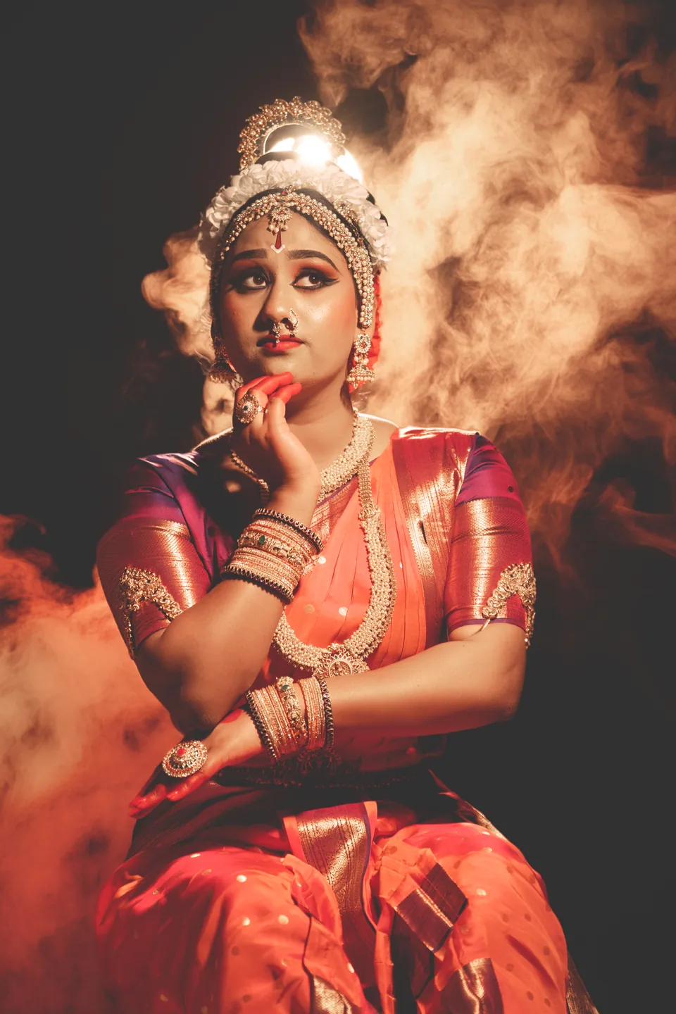 Classical dancer in red using expressive hand gestures against a smoky background