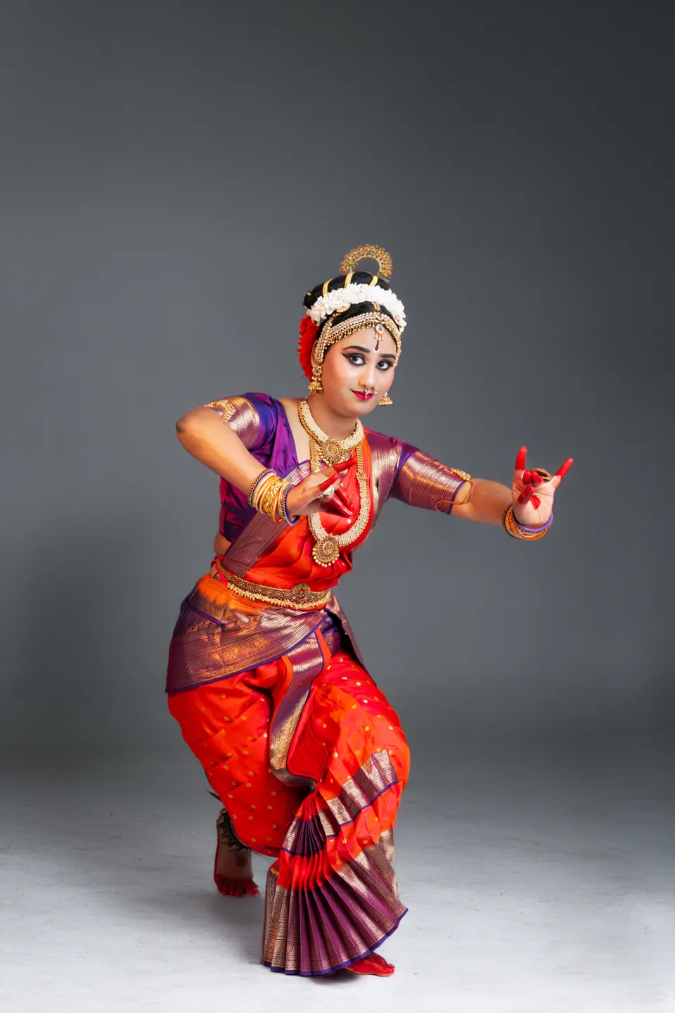 Classical dancer in red and purple in a poised studio stance