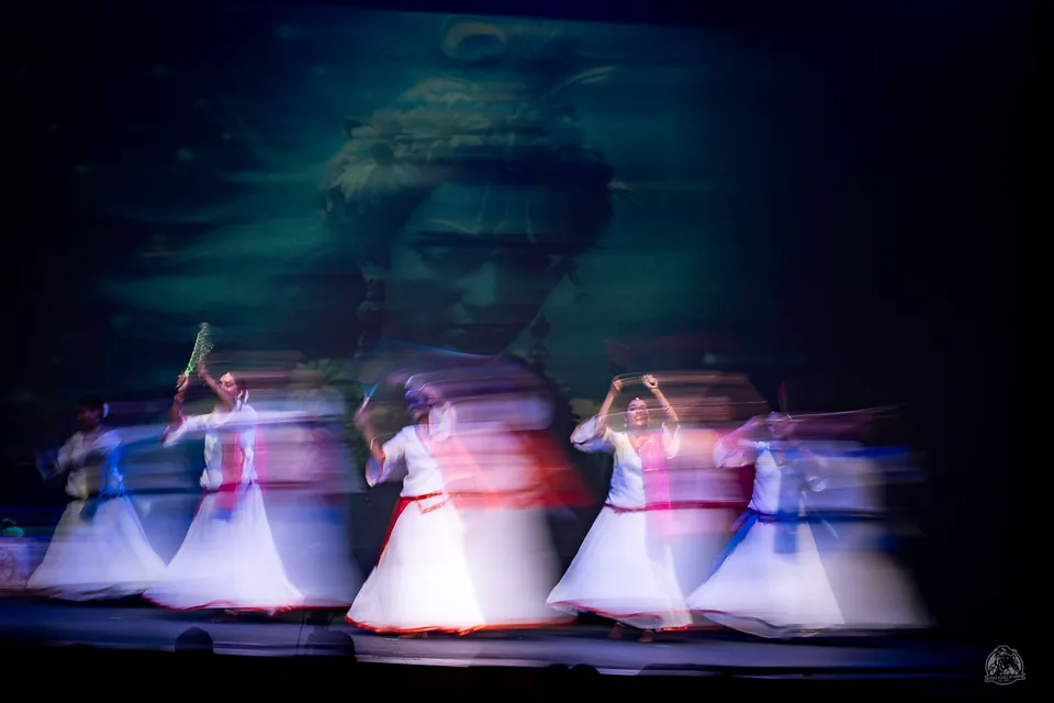 Dancers in pale costumes captured with flowing motion blur on stage