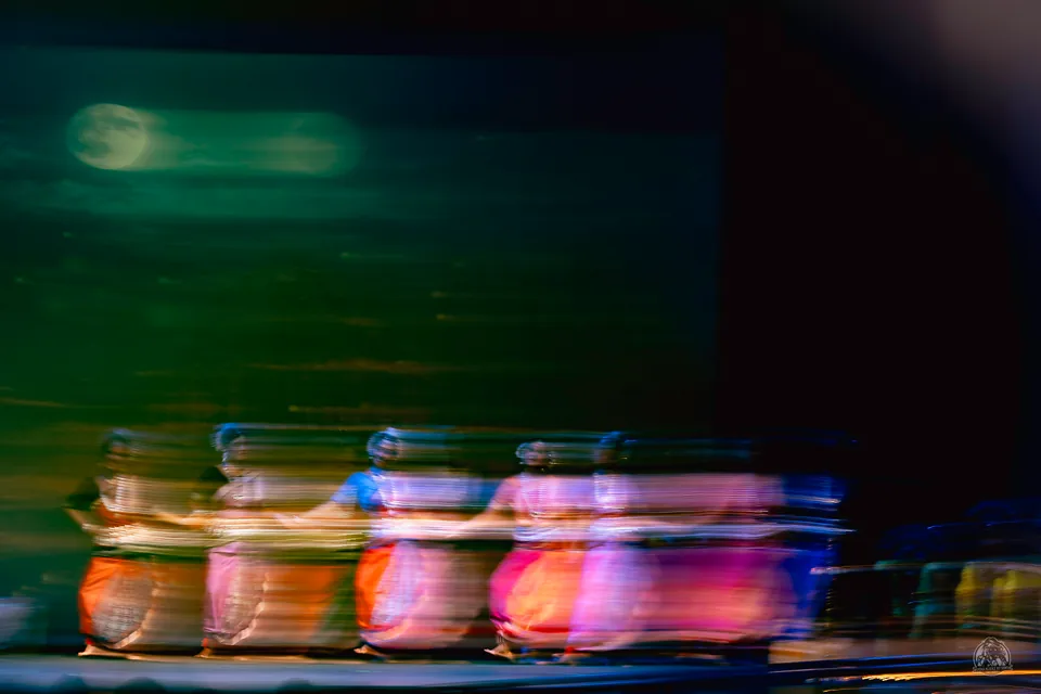Stage ensemble rendered as sweeping bands of color through intentional motion blur