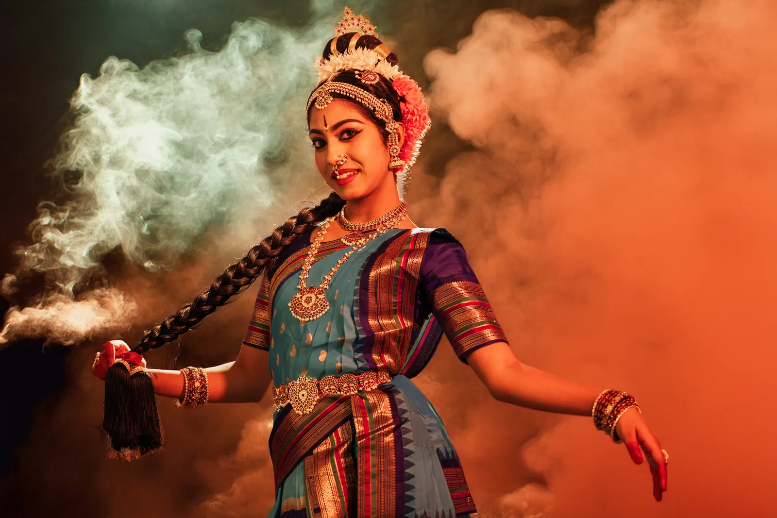 Classical dancer in turquoise and red surrounded by warm orange and pale smoke
