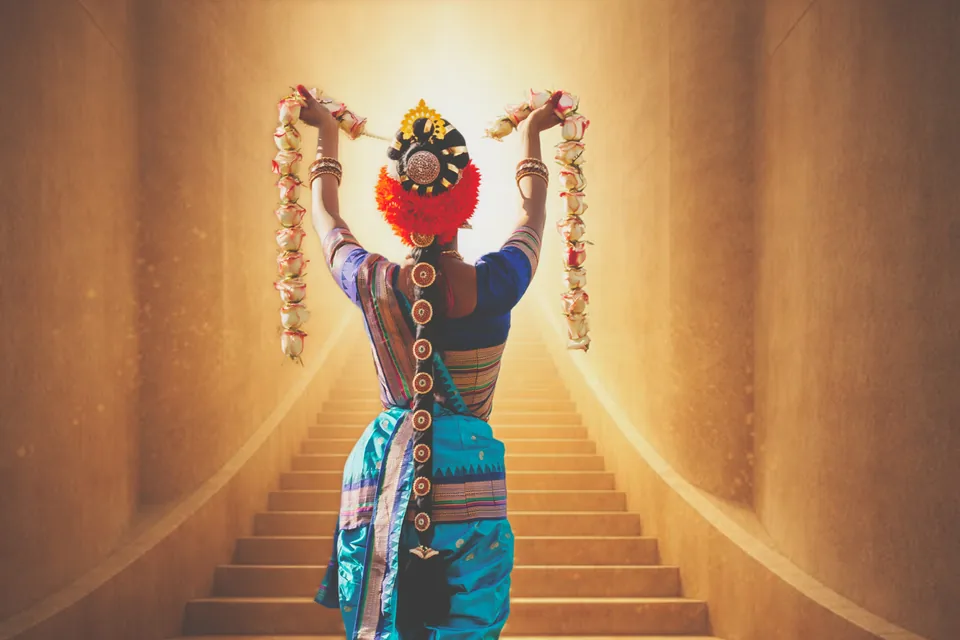 Classical dancer seen from behind with raised arms on a glowing staircase