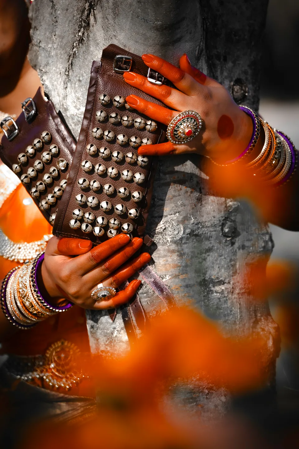 Close detail of a dancer holding ankle bells in warm light