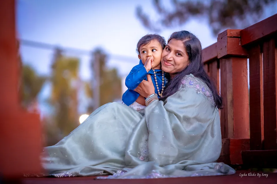 Woman sitting on a wooden bridge with a young child in her arms