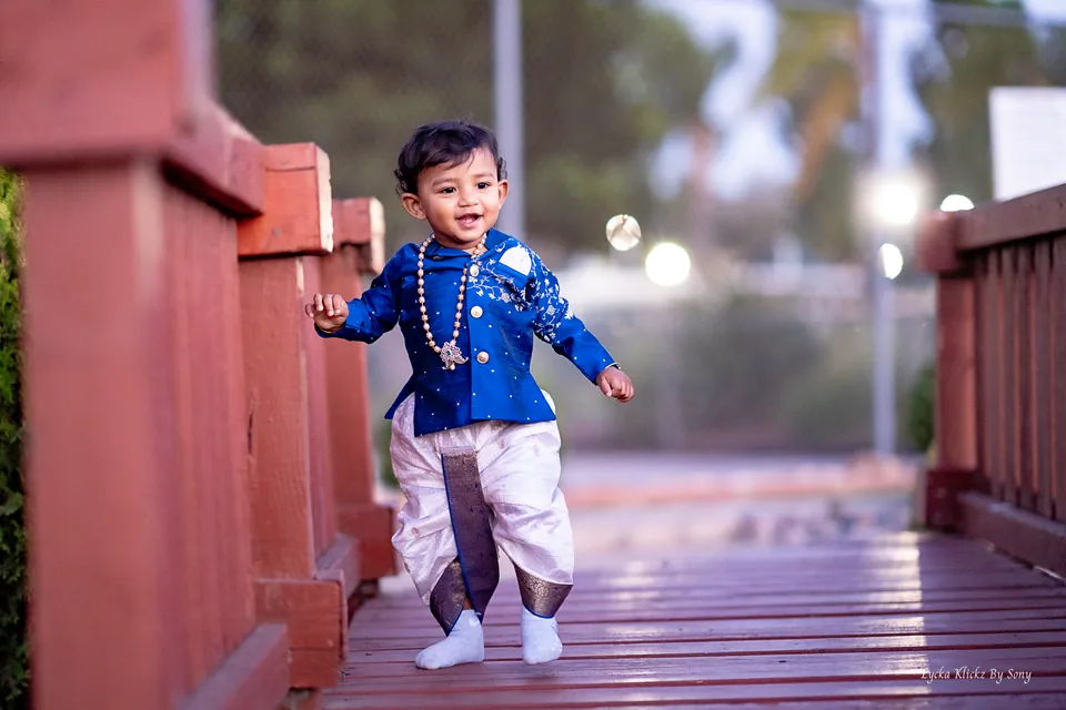 Young child in blue traditional clothing standing on a wooden bridge