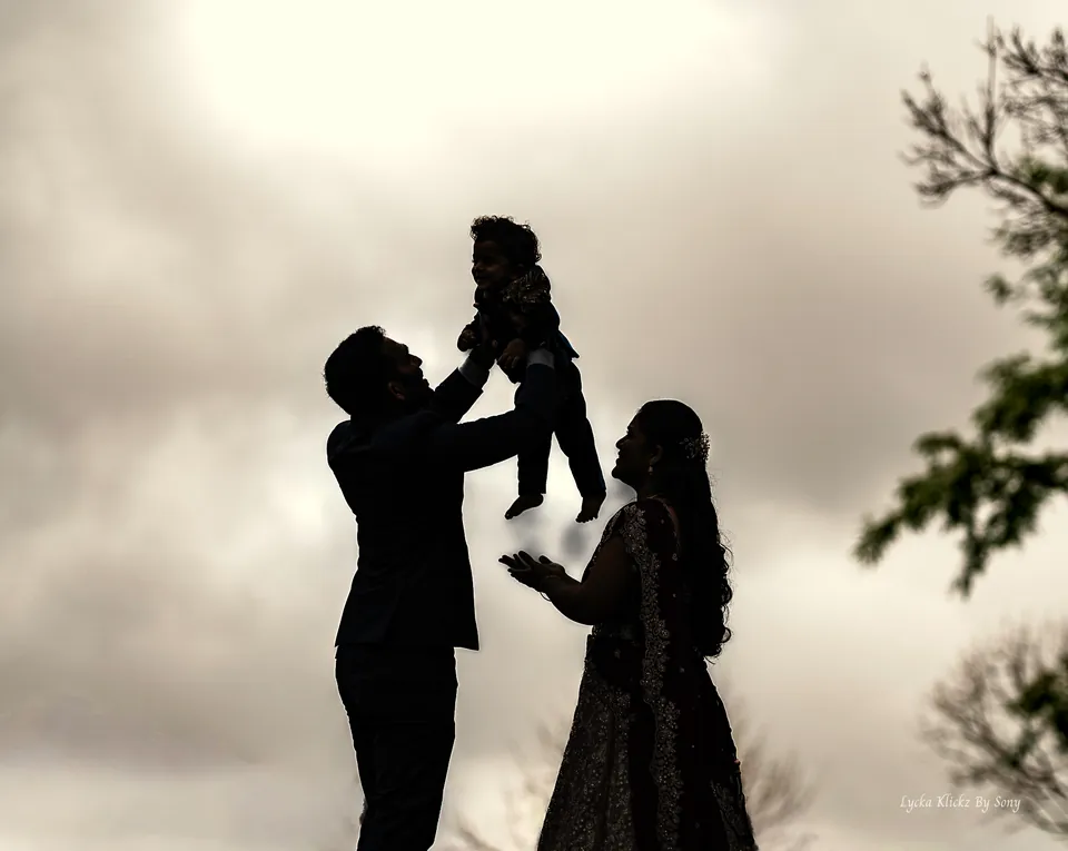 Silhouette of a family lifting a young child into the sky