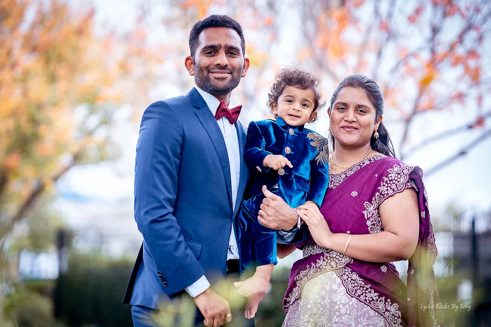 Family of three smiling together outdoors in formal clothing