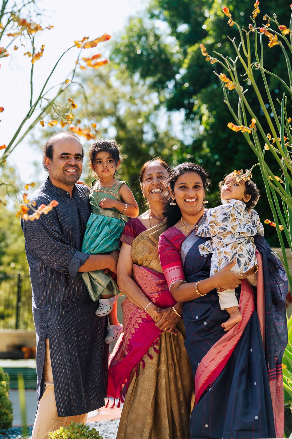 Two families with young children standing together beneath flowering trees