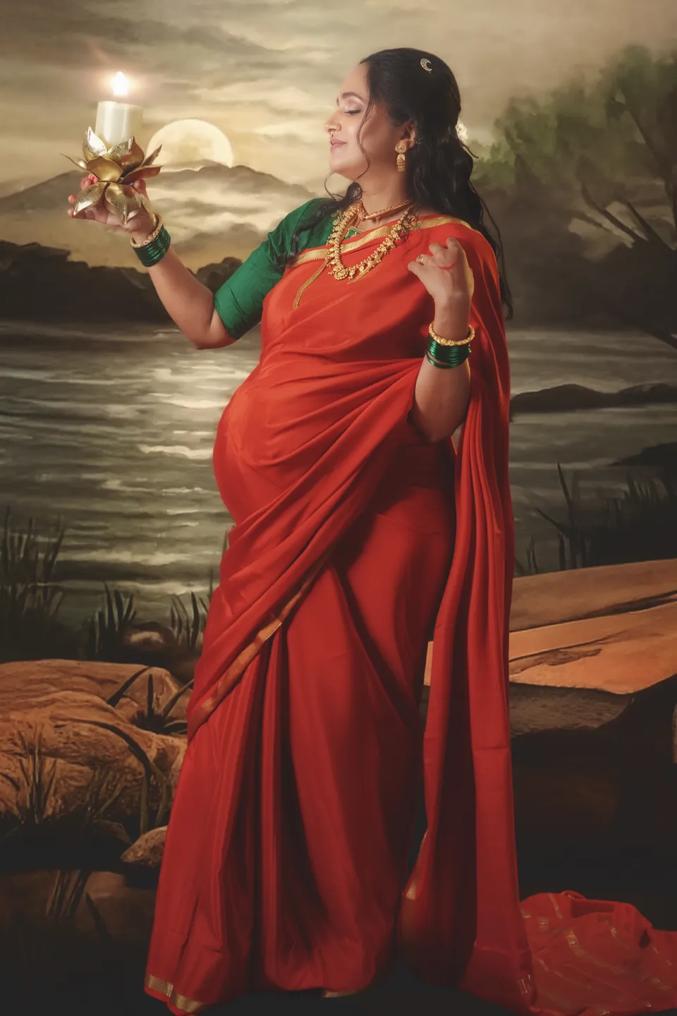 Expectant mother in a red sari holding a lit ceremonial plate