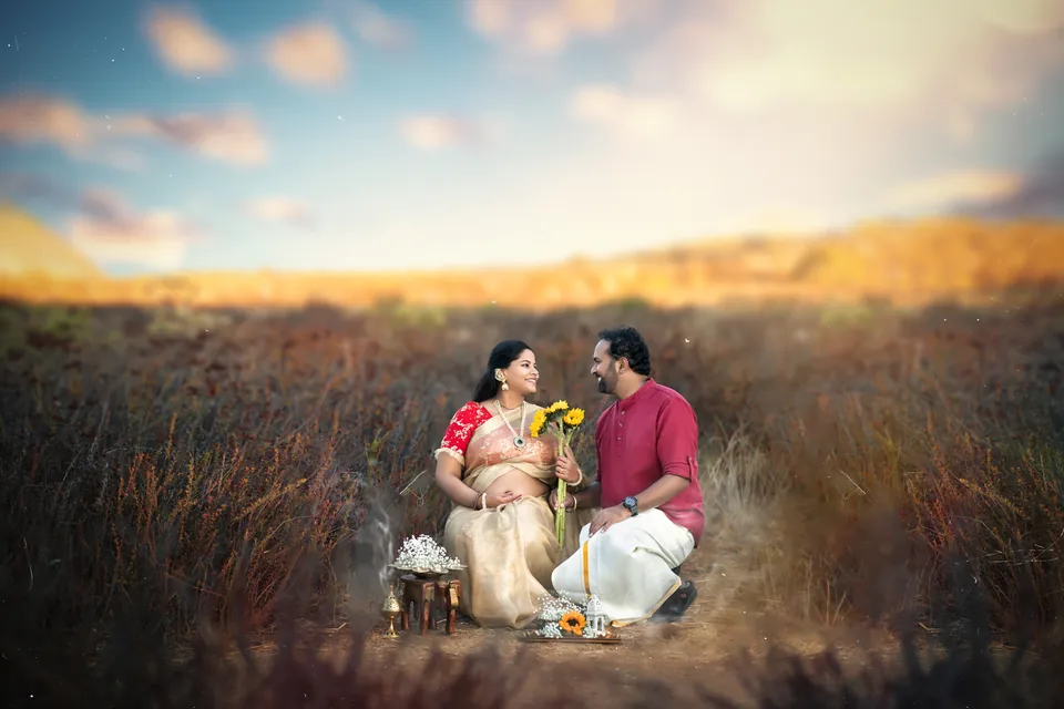 Expectant couple seated facing one another in a field