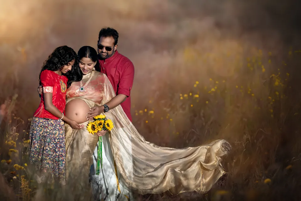 Family gathered around an expectant mother in a gold drape