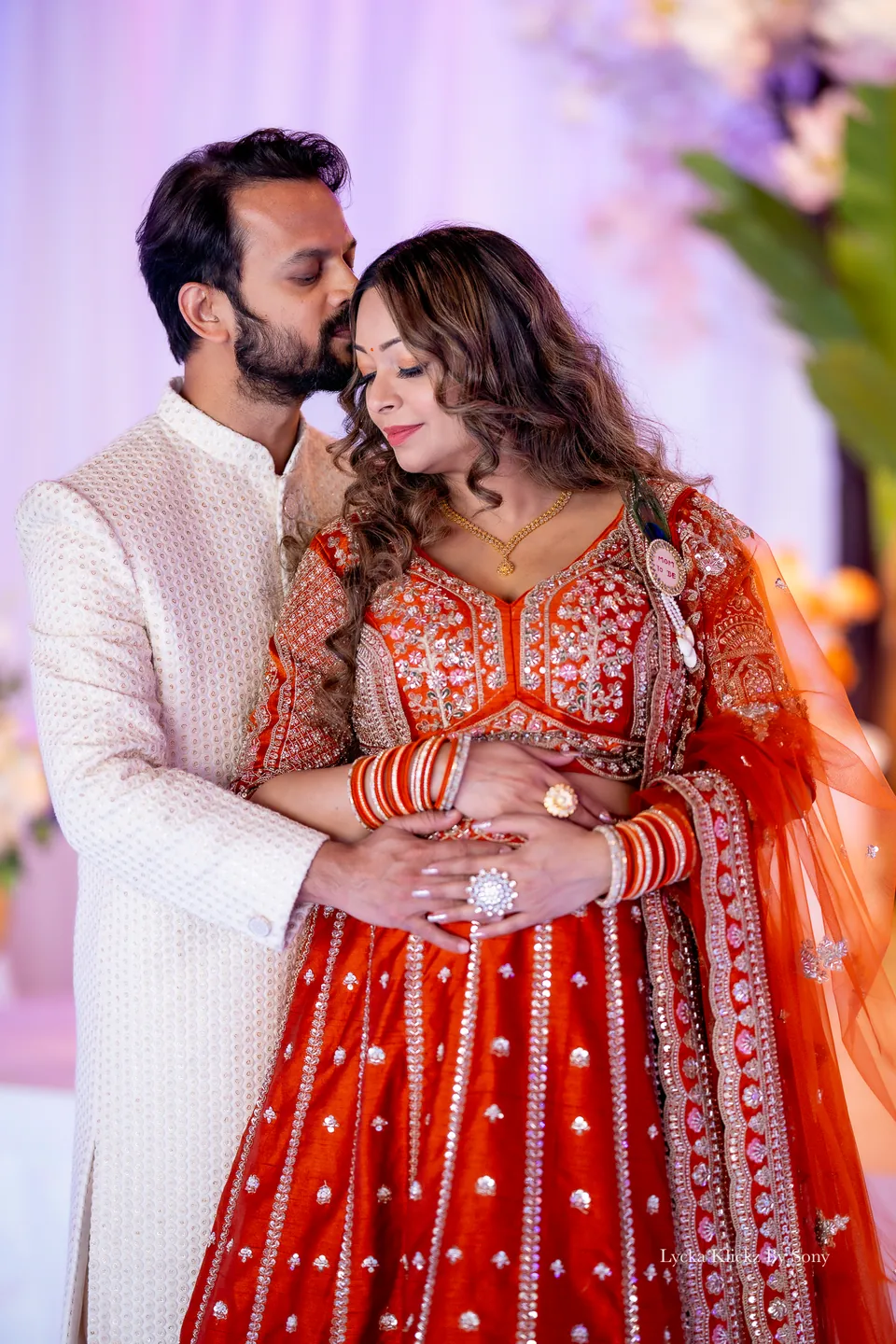 Couple sharing a quiet embrace in front of a decorated wedding stage