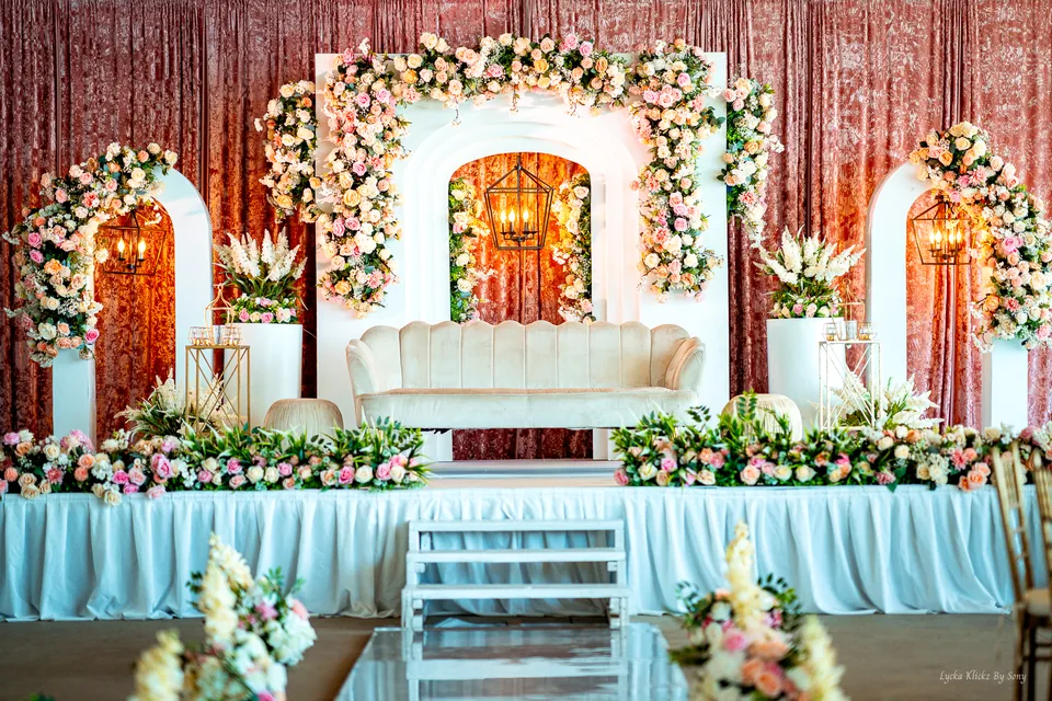 Wedding stage with white seating, gold frames, and floral arches
