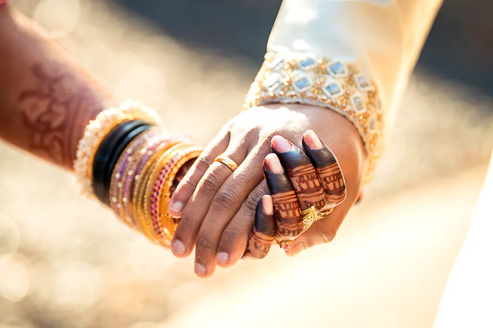 Wedding couple holding hands, with henna and jewelry in close detail