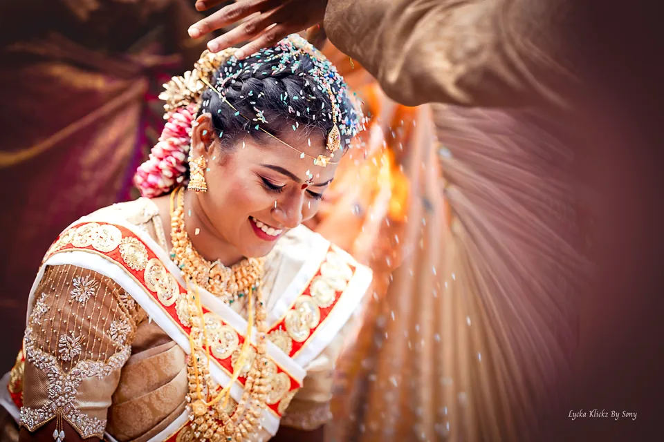 Bride smiling as grains fall over her hair during a wedding ceremony
