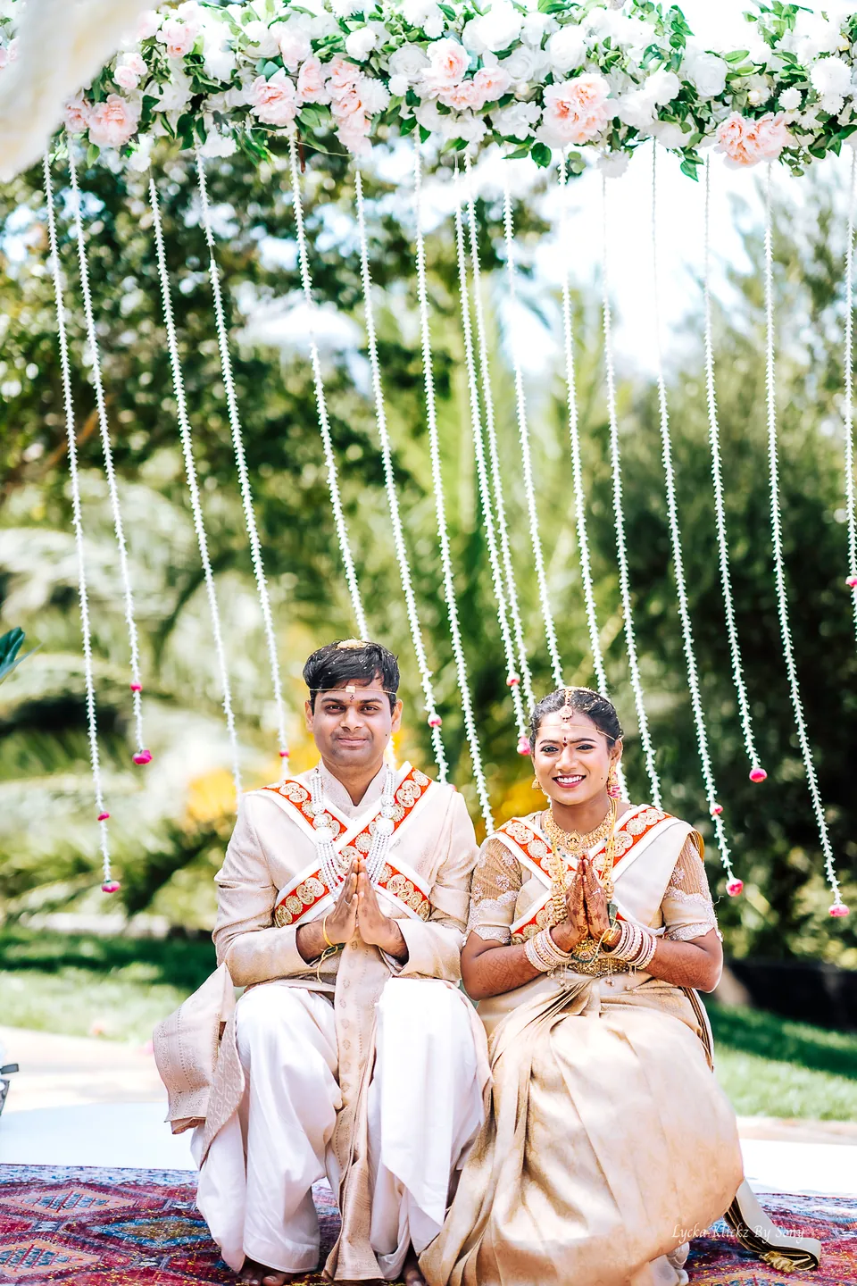 Wedding couple seated beneath a floral mandap