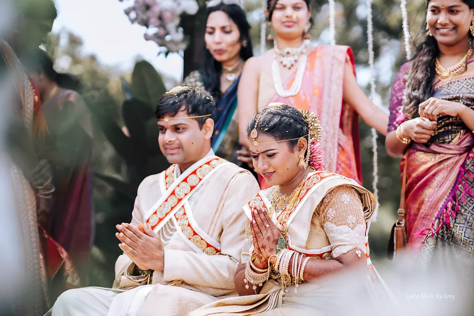 Couple seated together during a wedding ceremony, surrounded by guests