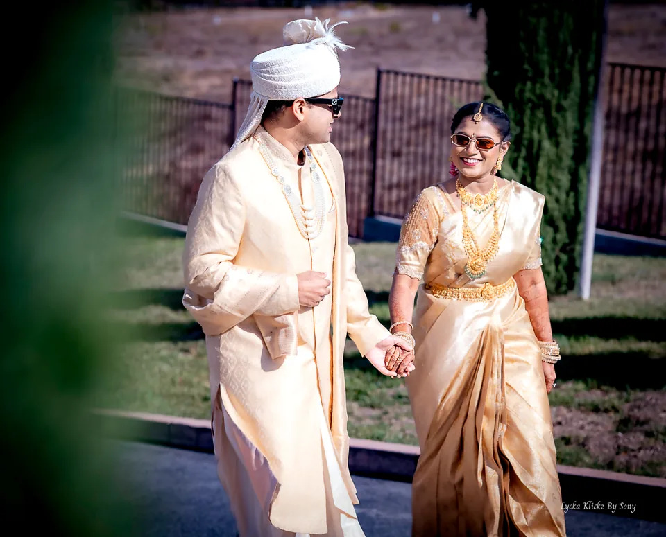 Wedding couple holding hands and smiling at one another outdoors