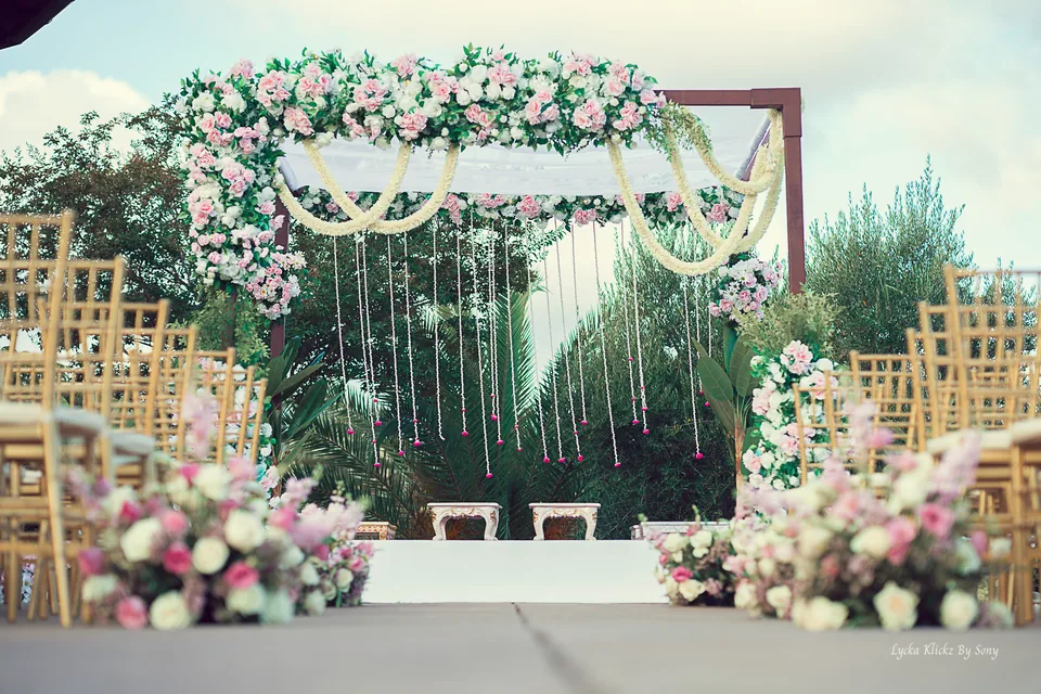 Outdoor wedding mandap decorated with pale flowers and hanging garlands