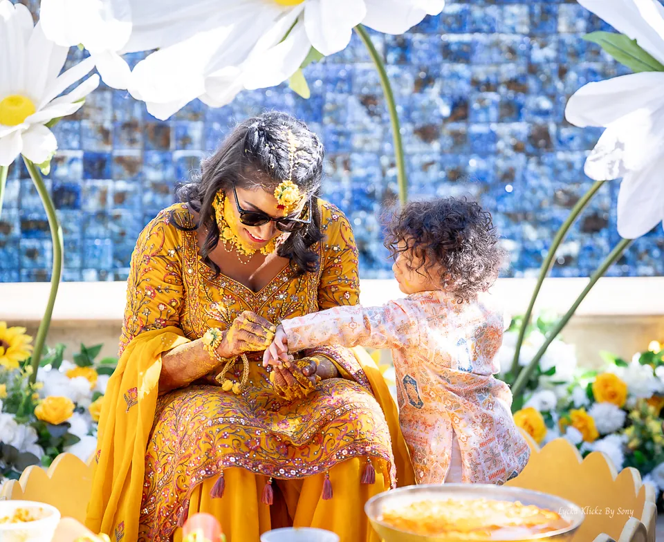 Woman in yellow smiling beside a young child during a pre-wedding celebration