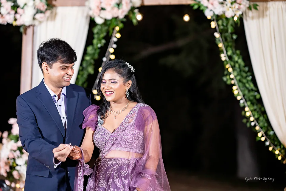 Couple exchanging rings with warm lights behind them