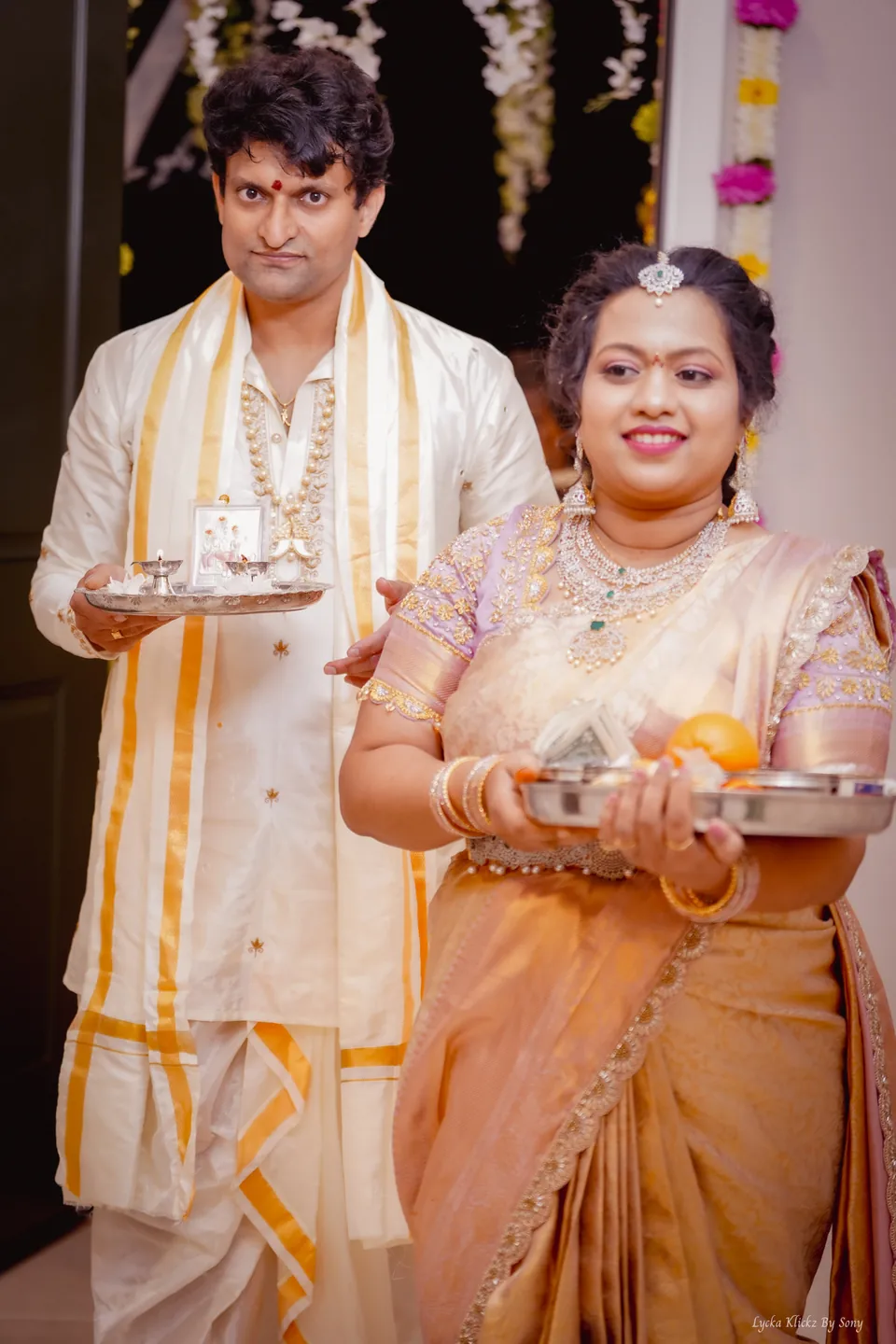 Couple in traditional clothing holding trays during a ceremony